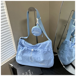Detail of light blue pleated tote bag with a small coin purse and fashion lettering