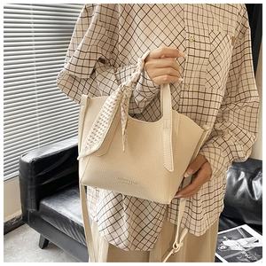 Sac seau chic en cuir crème avec détail foulard pied-de-poule sur un canapé en cuir