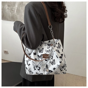 Detail of canvas tote bag featuring black butterfly prints and a silver decorative chain