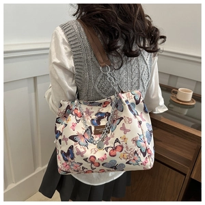 Close-up of butterfly print canvas tote bag with leather and metal chain straps
