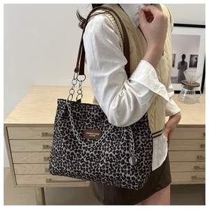 Detail of leopard print canvas tote bag with metal chain strap and leather logo patch