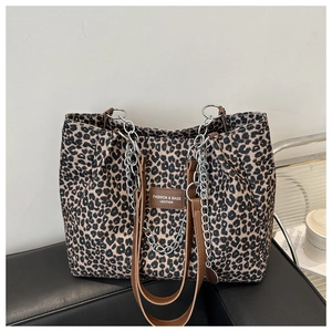 Detail of leopard print canvas tote bag featuring brown leather straps and silver metal chain