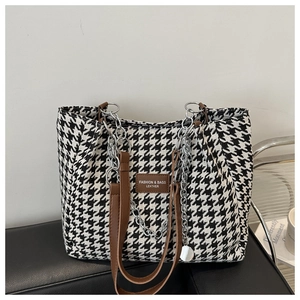 Close-up of houndstooth tote bag featuring leather handles and silver chain details