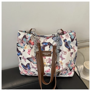Detail of colorful butterfly print tote bag with brown leather handle and silver metal chain