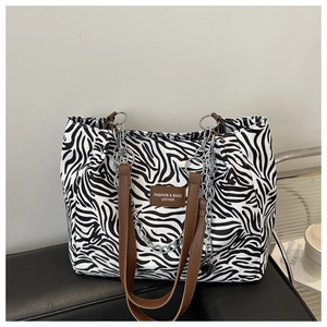 Detail of zebra print canvas tote featuring brown leather straps and silver metal chains