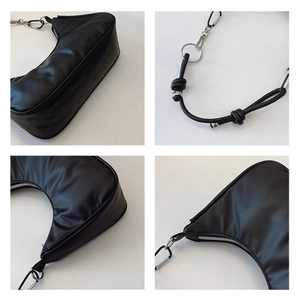 Detail view of black crescent shoulder bag featuring silver hardware and knotted strap details