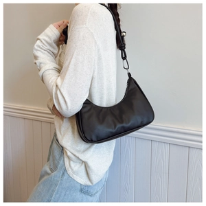 Close-up of black crescent shoulder bag with silver ball charms and metal zipper detail