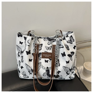 Close-up of white canvas tote bag with butterfly print, leather handle, and silver chain