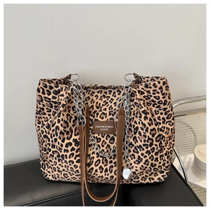Close-up of leopard print canvas tote bag featuring silver chain and leather logo tag