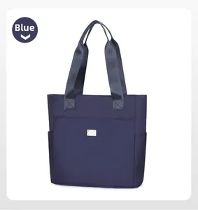 Detail of the blue nylon tote bag showing the silver metal logo plaque and side pocket
