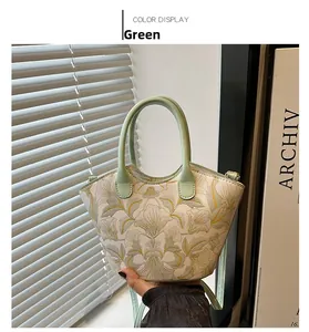 Close-up of floral embroidery on a white and green vintage tote bag with leather handle