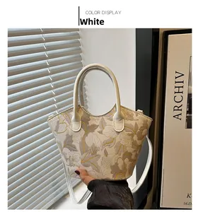 Detail of white handbag with exquisite gold and grey floral embroidery and top handles