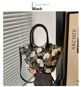 Detailed close-up of a black bucket bag with intricate floral embroidery and leather handles