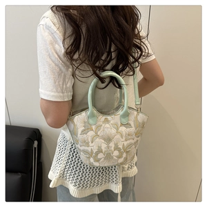 Détail du dos du mannequin portant un sac seau blanc avec broderie florale et bandoulière verte