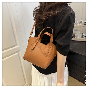 Detailed back view of a brown pebbled leather tote bag worn as a shoulder bag