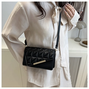 Detail of black quilted shoulder bag with geometric stitching and gold metal trim on flap