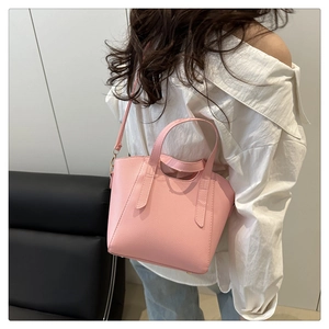 Pink tote bag in pebble grain faux leather shown on shoulder with long slim strap