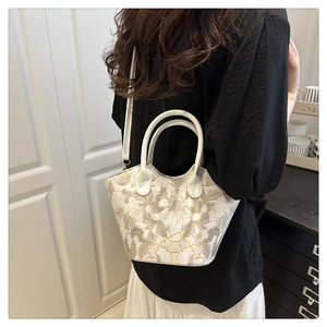 Detailed embroidery on white Boston tote bag with gold hardware and top handle