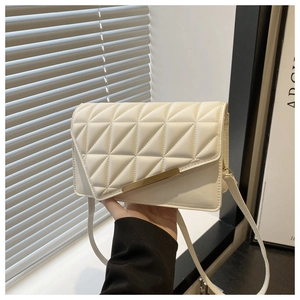 Détail d'un petit sac beige matelassé avec garniture dorée et fine bandoulière chic