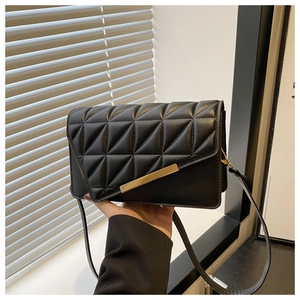 Détail d'un sac bandoulière noir matelassé avec surpiqûres et garniture en métal doré