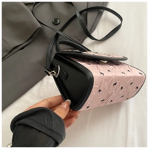 Detail of pink ruffled texture with black bow pattern and leather side on mini handbag