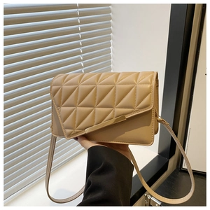 Détail du sac bandoulière beige en similicuir matelassé avec barre dorée chic