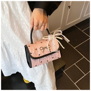 Detail of pink pleated handbag featuring black bow prints and pearl lace ribbon accessories