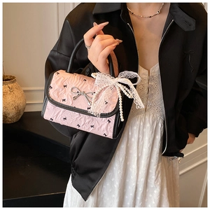 Detail of pink pleated handbag with black bow patterns and elegant pearl lace charm