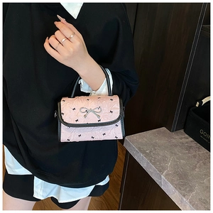 Detail of pink pleated crossbody bag with black bow prints and metal buckle