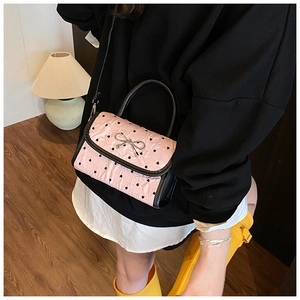 Detail of pink crossbody bag with black heart prints and silver metal bow ornament