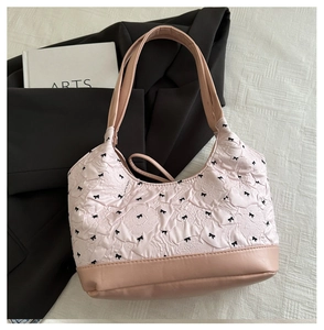 Detail shot of a pink bow-patterned handbag on a black blazer with soft lighting