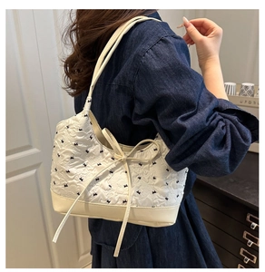 Detail of embroidered bow patterns on a chic cream crossbody bag for women