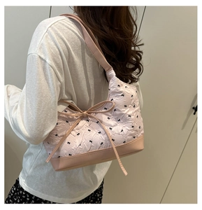 Close-up of pink underarm bag with pleated texture and black bow print details