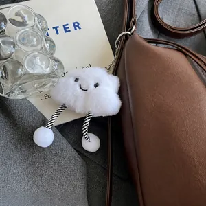Close-up of white plush cloud charm with striped legs on a brown leather bag