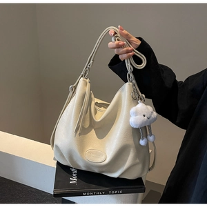 Detail of creamy white tote bag featuring natural texture and cloud charm decoration