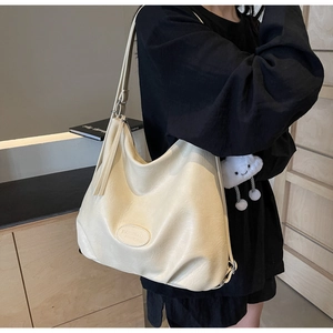 Detail of cream hobo tote bag with lychee texture and plush cloud charm worn by model