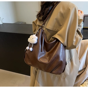 Detail view of brown leather tote bag texture with cute cloud pendant and logo tag