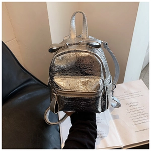 Detail of silver metallic mini backpack with bow decoration and snakeskin texture