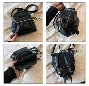 Detail view of mini black glossy leather backpack showing front, side and back compartments