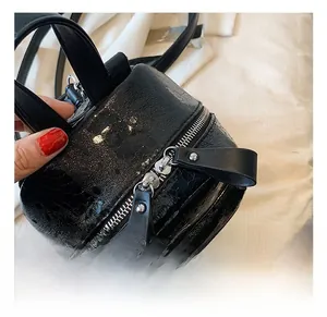 Detail showing the glossy crocodile-embossed black leather and silver zippers on the backpack