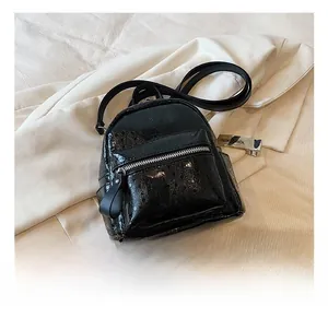 Close-up of black glossy patent leather mini backpack with silver metal zippers