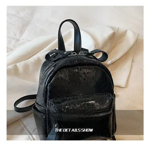 Detail of black mini backpack featuring a glossy cracked texture and cute bow accent