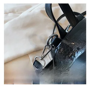 Close-up of black glossy crocodile-patterned backpack with silver metal rotating hooks