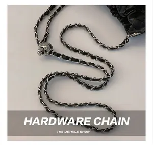 Close-up of silver chain strap with spherical metal buckle on black woven leather bag
