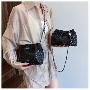 Detail of black woven leather bucket bag with silver chain strap and metal ball charms