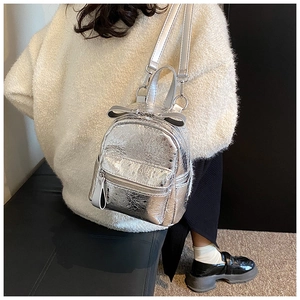 Close-up of silver shiny mini backpack with bow detail and textured metallic leather finish