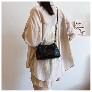 Detail of black woven leather shoulder bag with chain strap and soft pleated closure