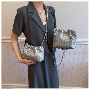 Detail of silver woven bucket bag featuring intricate metallic leather texture and chain strap