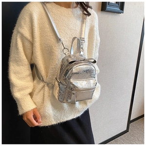Detail of silver metallic mini backpack with bow decoration and crinkled texture