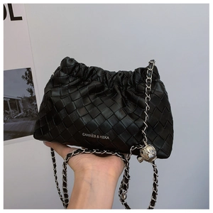 Detail of black woven leather bucket bag with silver chain strap and metal ball charm